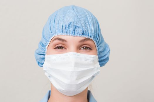 Dentist in surgical mask and cap looking at camera at the dental clinic