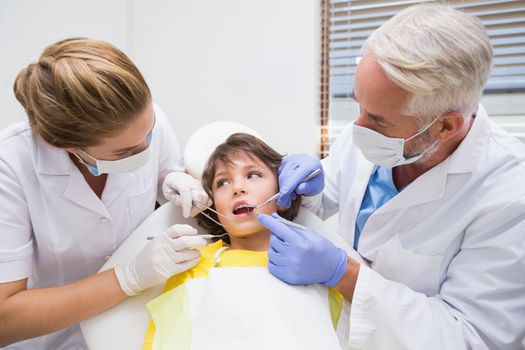 Pediatric dentist examining a little boys teeth with his assistant at the dental clinic