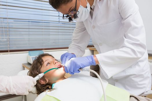 Pediatric dentist examining a little boys teeth in the dentists chair at the dental clinic