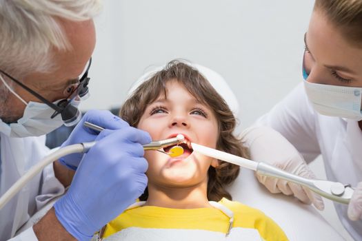 Pediatric dentist and assistant examining a little boys teeth at the dental clinic