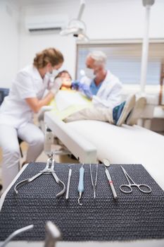 Pediatric dentist examining a little boys teeth with his assistant at the dental clinic