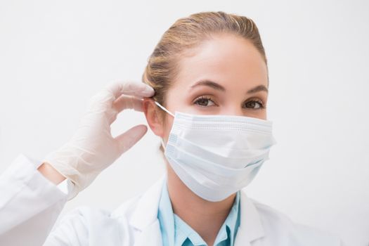 Dentist putting on her surgical mask at the dental clinic