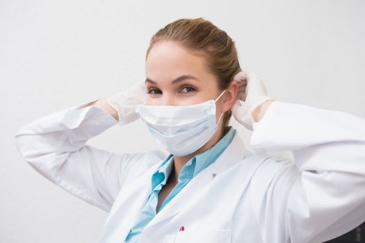 Dentist putting on her surgical mask at the dental clinic
