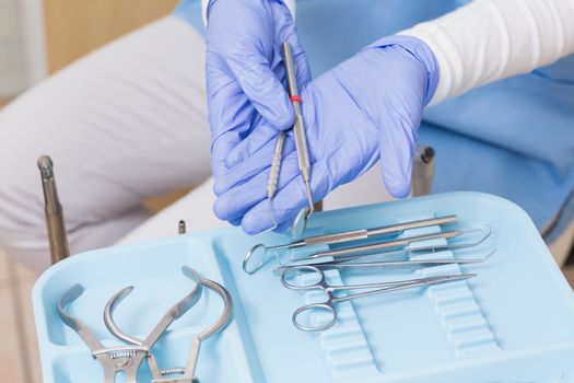 Dentist in blue scrubs holding dental tools at the dental clinic