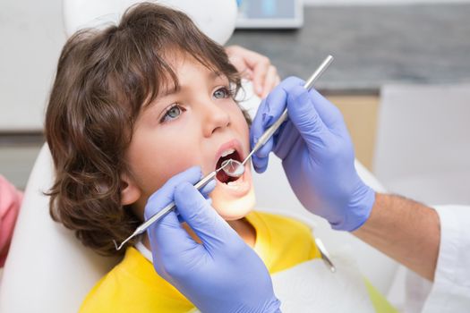 Pediatric dentist examining a little boys teeth in the dentists chair at the dental clinic