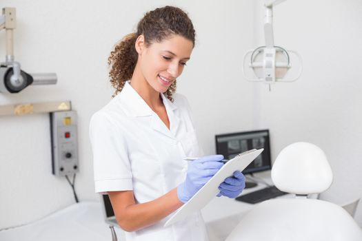 Dental assistant writing in clipboard at the dental clinic