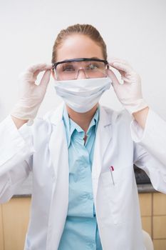 Dentist putting on her protective glasses at the dental clinic