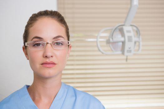 Dentist in blue scrubs looking at camera at the dental clinic