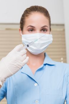 Dental assistant holding injection looking at it at the dental clinic