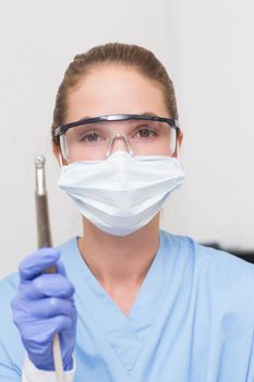 Dentist in blue scrubs holding dental drill at the dental clinic