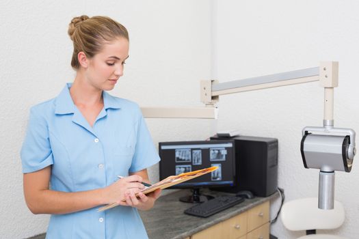 Dental assistant writing in folder at the dental clinic