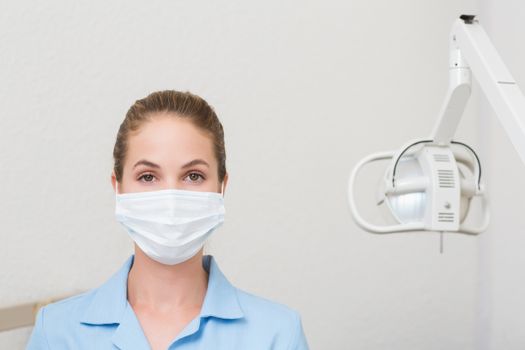 Dental assistant in mask looking at camera at the dental clinic