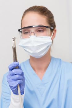 Dentist in blue scrubs holding dental drill at the dental clinic
