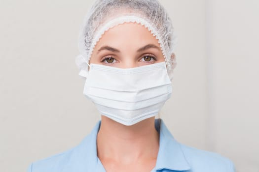 Dentist in surgical mask and cap looking at camera at the dental clinic