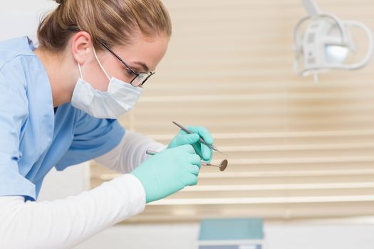 Dentist in blue scrubs holding dental tools at the dental clinic