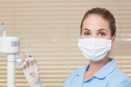 Dental assistant holding injection looking at camera at the dental clinic