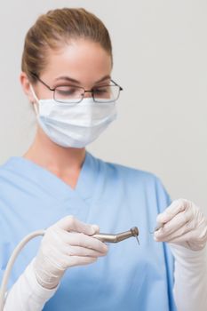 Dentist in blue scrubs holding drill at the dental clinic