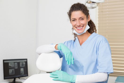 Dentist in blue scrubs smiling at camera at the dental clinic