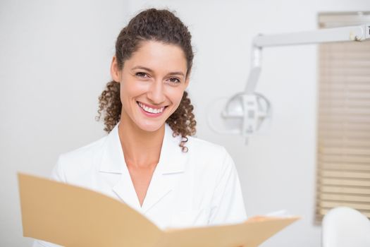 Dental assistant reading from file at the dental clinic