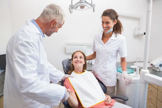Dentist shaking hands with his patient in the chair at the dental clinic