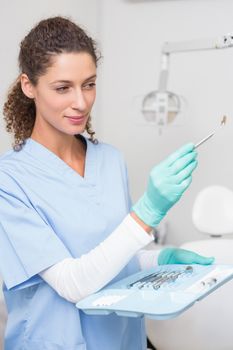 Dentist in blue scrubs holding tray of tools at the dental clinic