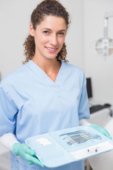 Dentist in blue scrubs holding tray of tools at the dental clinic