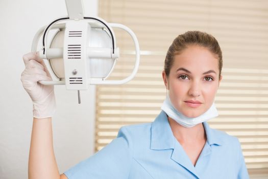 Dental assistant smiling at camera beside light at the dental clinic