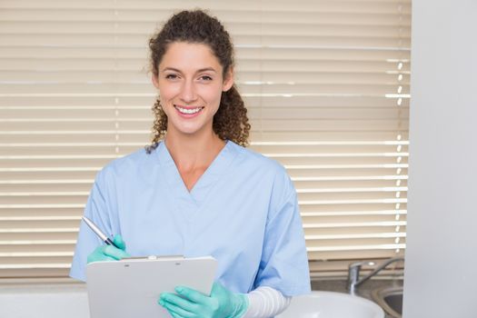 Dentist in blue scrubs writing on clipboard at the dental clinic
