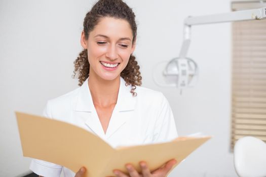 Dental assistant reading from file at the dental clinic