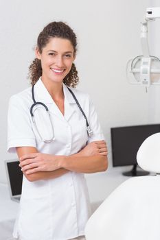 Dental assistant smiling at camera beside chair at the dental clinic