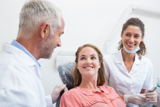 Dentist talking with patient while nurse prepares the tools at the dental clinic