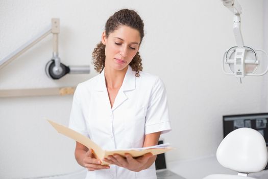 Dental assistant reading from file at the dental clinic