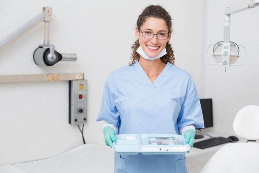 Dentist in blue scrubs holding tray of tools at the dental clinic