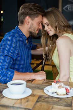 Close up of romantic couple with eyes closed sitting on chair in cafe shop 