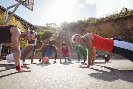 Basketball players performing push up exercise in basketball court outdoors