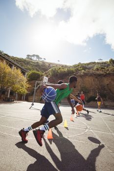 Basketball players practicing dribbling drill  in basketball court outdoors