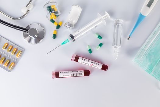 Blood test tube with the Coronavirus disease for virus test and research. Blood test tube with protective masks, medicines, thermometer, stethoscope and syringe on a white background.