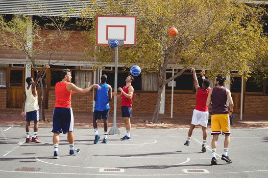 Basketball players practicing in basketball court outdoors