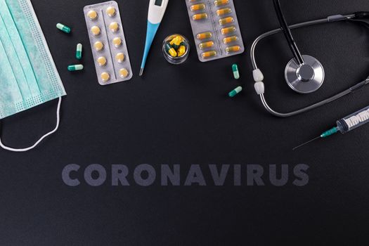 Protective masks, medicines, thermometer, stethoscope and syringe with coronavirus text on a black background. Novel coronavirus 2019-nCoV, MERS-Cov middle East respiratory syndrome coronavirus.