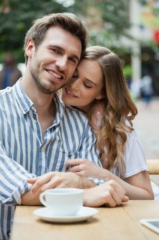 Happy romantic couple sitting at sidewalk cafe in city