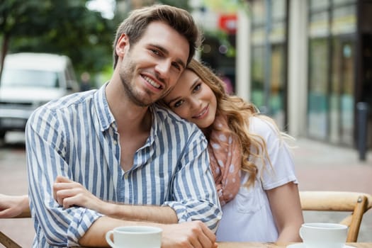 Portrait of romantic couple sitting at sidewalk cafe in city