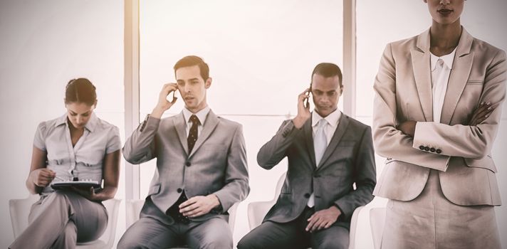 Businesswoman standing in front of business people waiting in a row