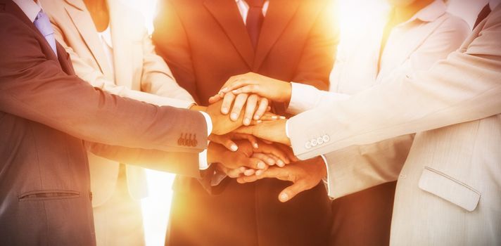 Group of smiling business people piling up their hands together in the workplace
