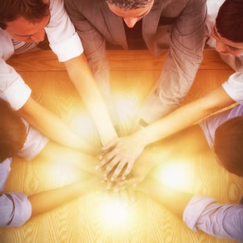 High angle view of business team stacking hands on table in office