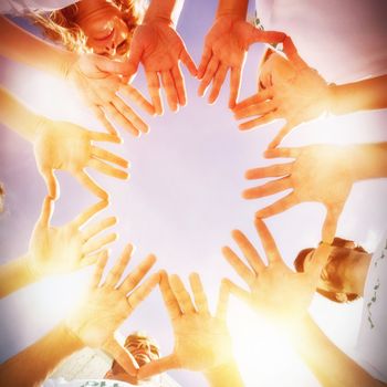 Low angle view of volunteers with hands together against blue sky