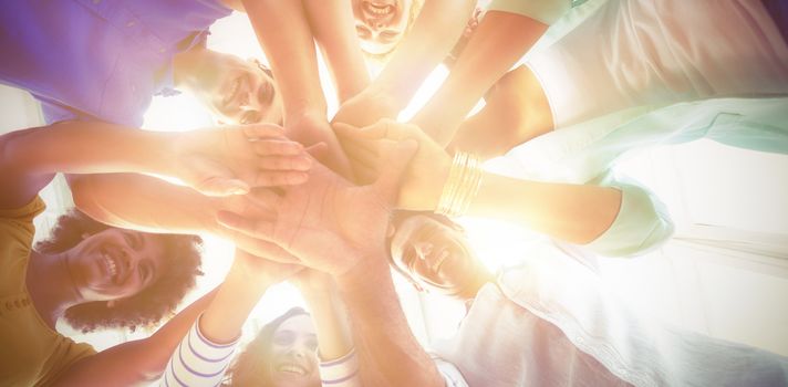 Cheerful business people stacking hands while standing in office