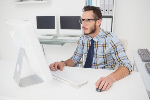 Happy casual businessman working at his desk in his office