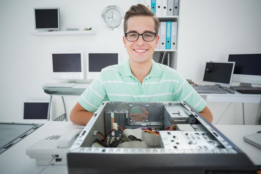 Smiling technician working on broken computer in his office