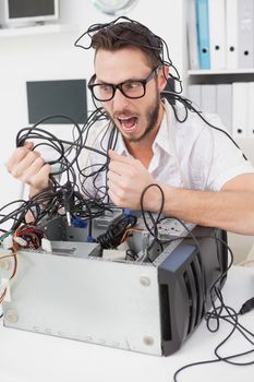 Angry computer engineer pulling wires in his office