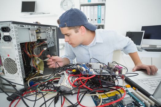 Computer engineer working on broken console with laptop in his office